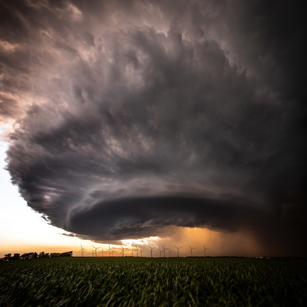 Dramatic thunderstorm over a cornfield with wind turbines on the horizon, extreme weather